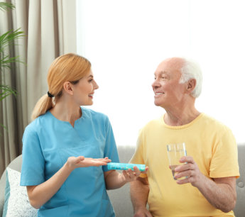 nurse giving medication to elderly man indoors